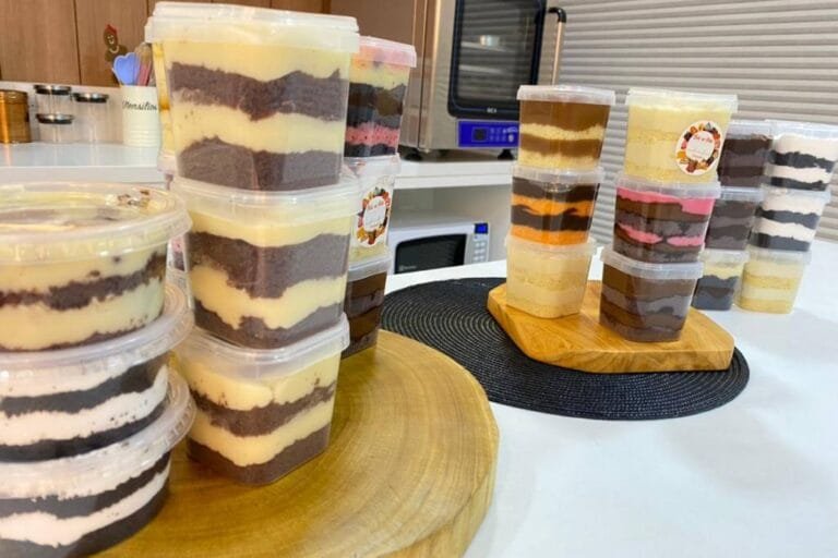 Vários potes de bolo de pote para vender, com adesivos na tampa, prontos para um negócio lucrativo em casa.