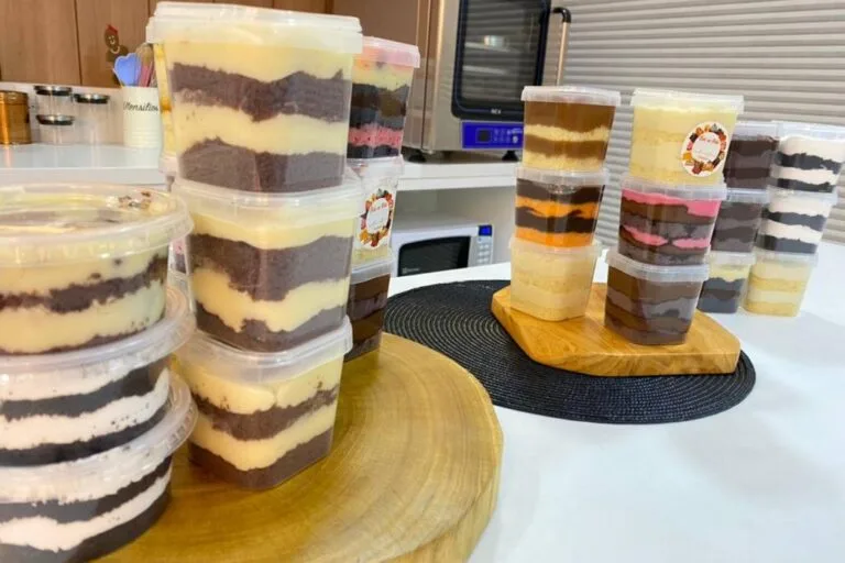 Vários potes de bolo de pote para vender, com adesivos na tampa, prontos para um negócio lucrativo em casa.