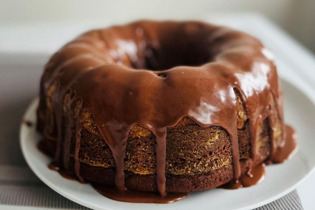 Calda de brigadeiro cremosa caindo sobre um bolo de chocolate fofinho e quente