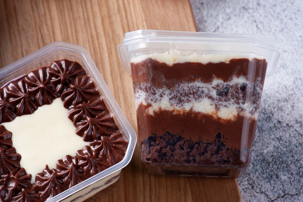 Confeiteira usando luz natural para tirar uma foto atraente de bolo de pote para vender no Instagram.