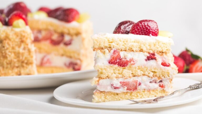 Fatia de bolo com massa branca e recheio generoso de creme com morangos frescos, mostrando a harmonização perfeita.