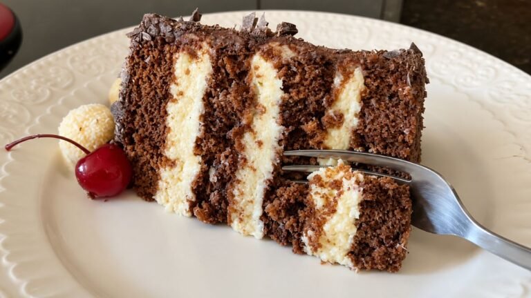 Fatia de bolo de chocolate com recheio de beijinho trufado cremoso e docinho de coco na decoração.